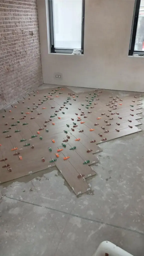 Pose de carrelage dans une pièce aux murs en brique