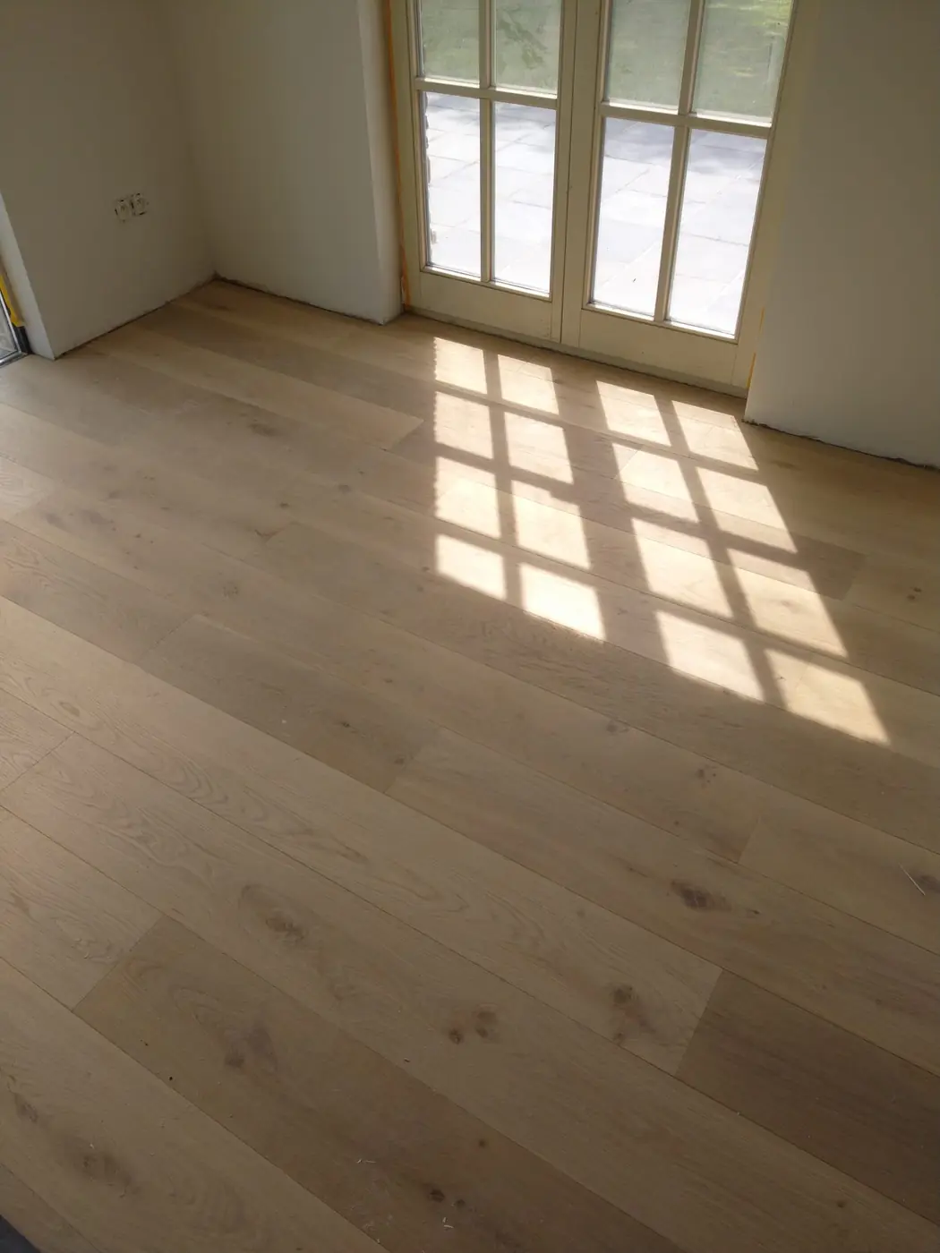 Parquet en chêne à larges lames près d’une porte-fenêtre