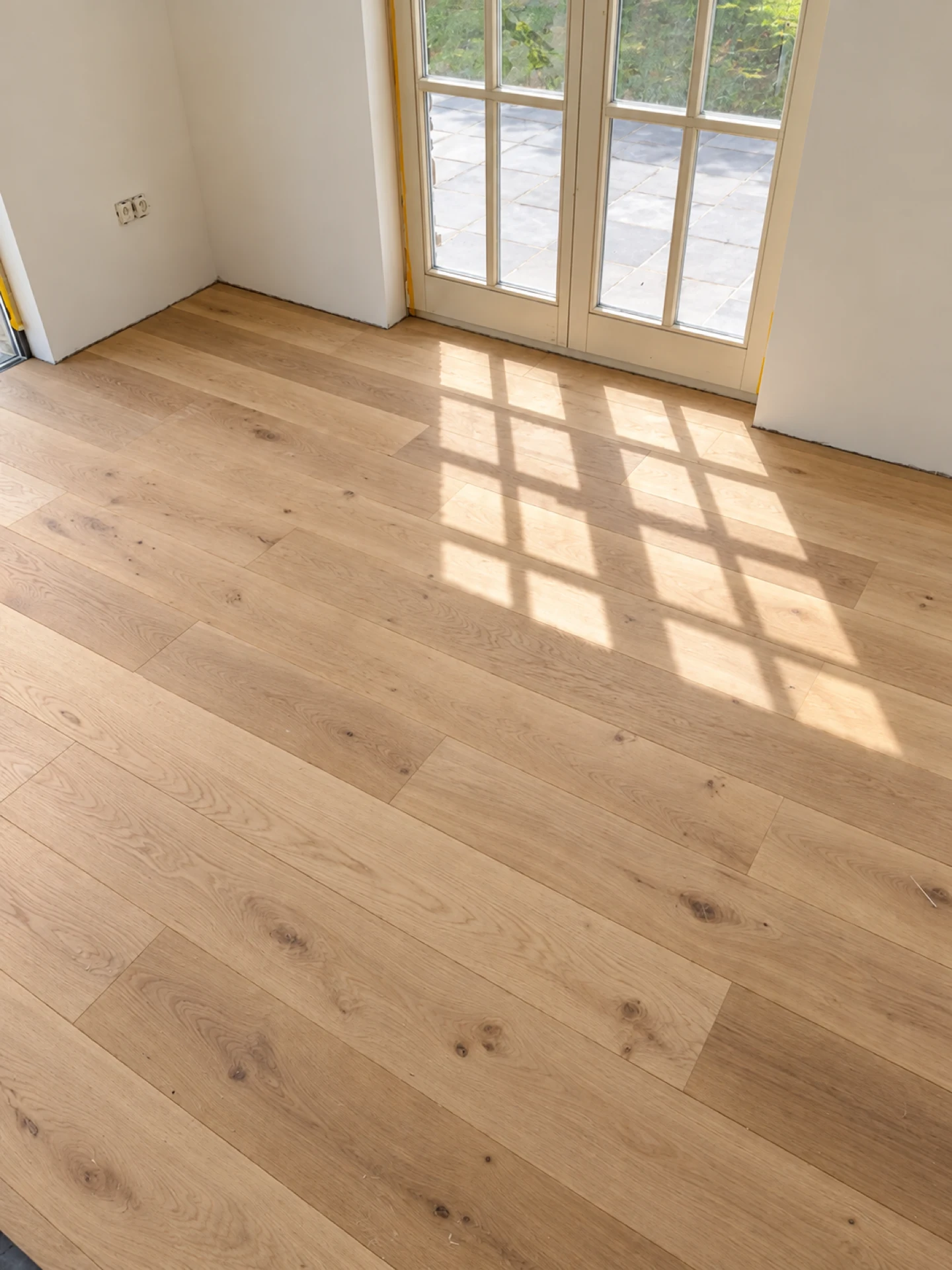 Parquet en chêne à larges lames près d’une porte-fenêtre