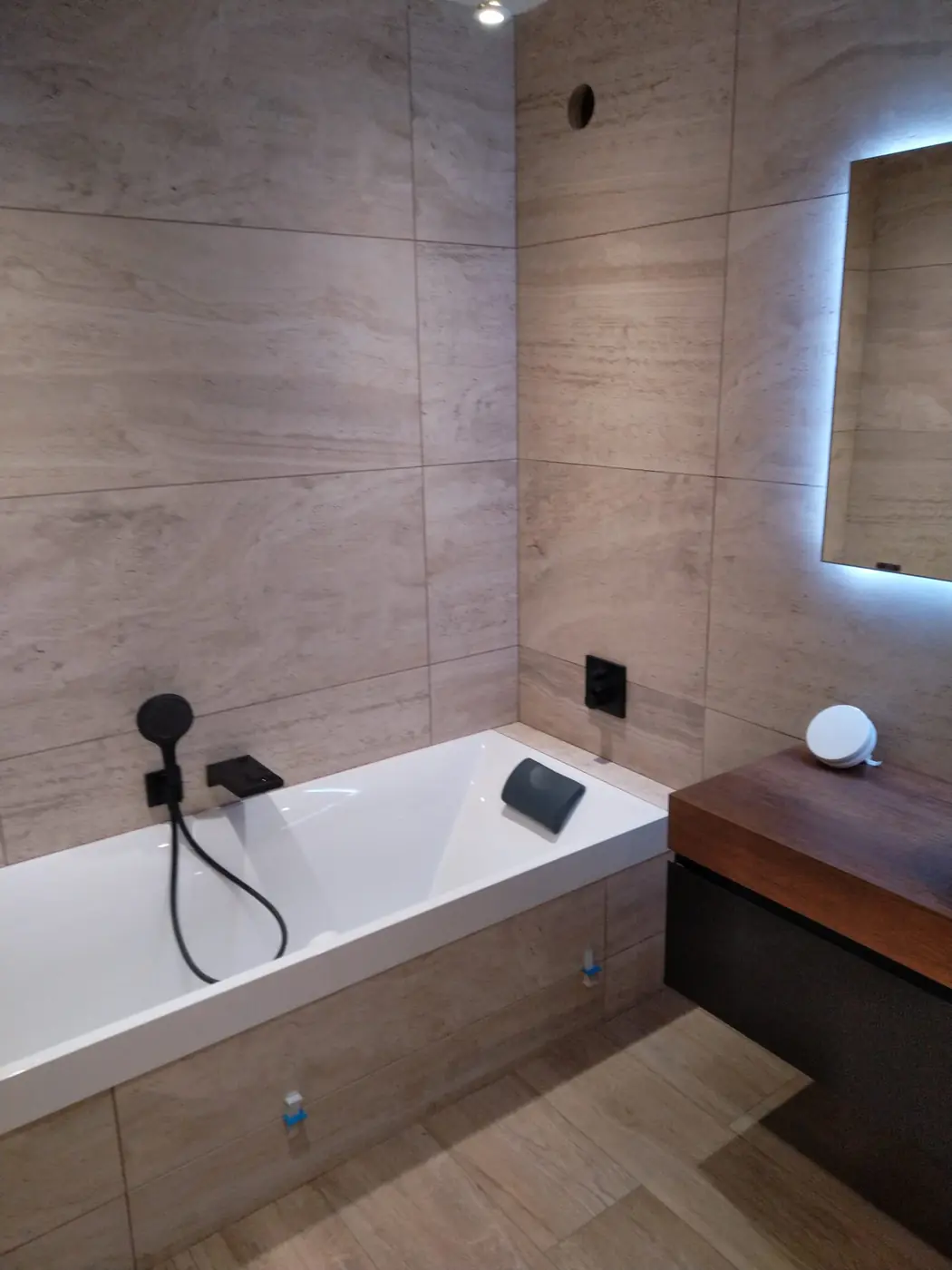 Salle de bain rénovée avec baignoire habillée et carrelage grand format effet pierre