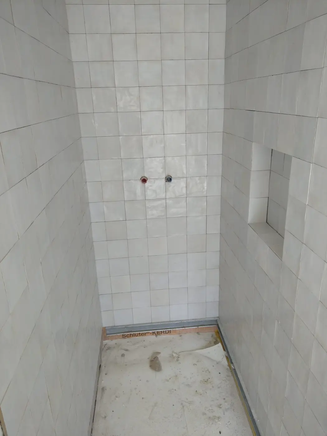 Douche carrelée en faïence blanche avec niche encastrée